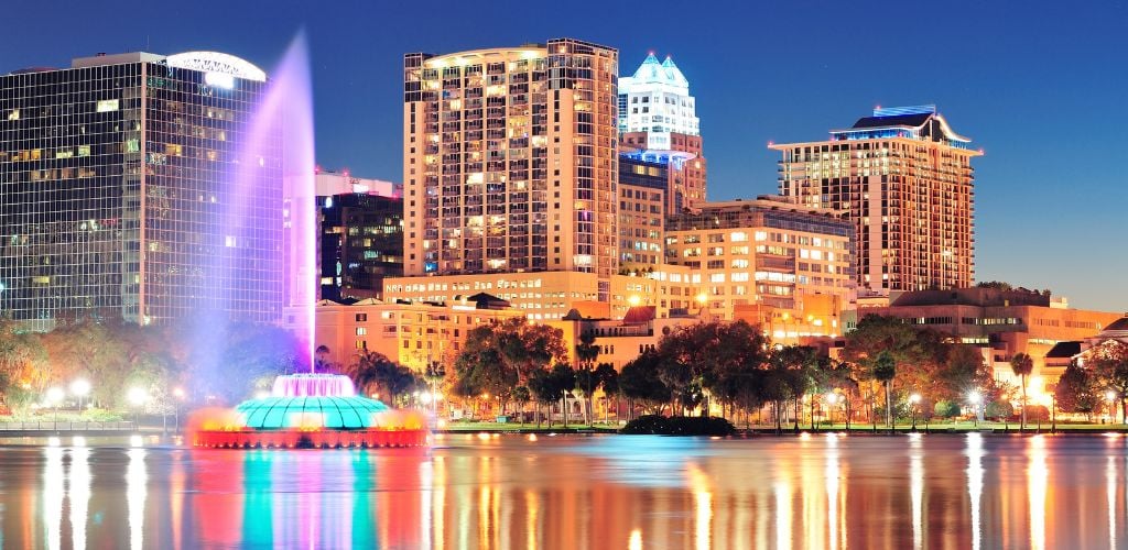 Orlando downtown skyline over Lake Eola at night with urban skyscrapers. fountain and clear sky.